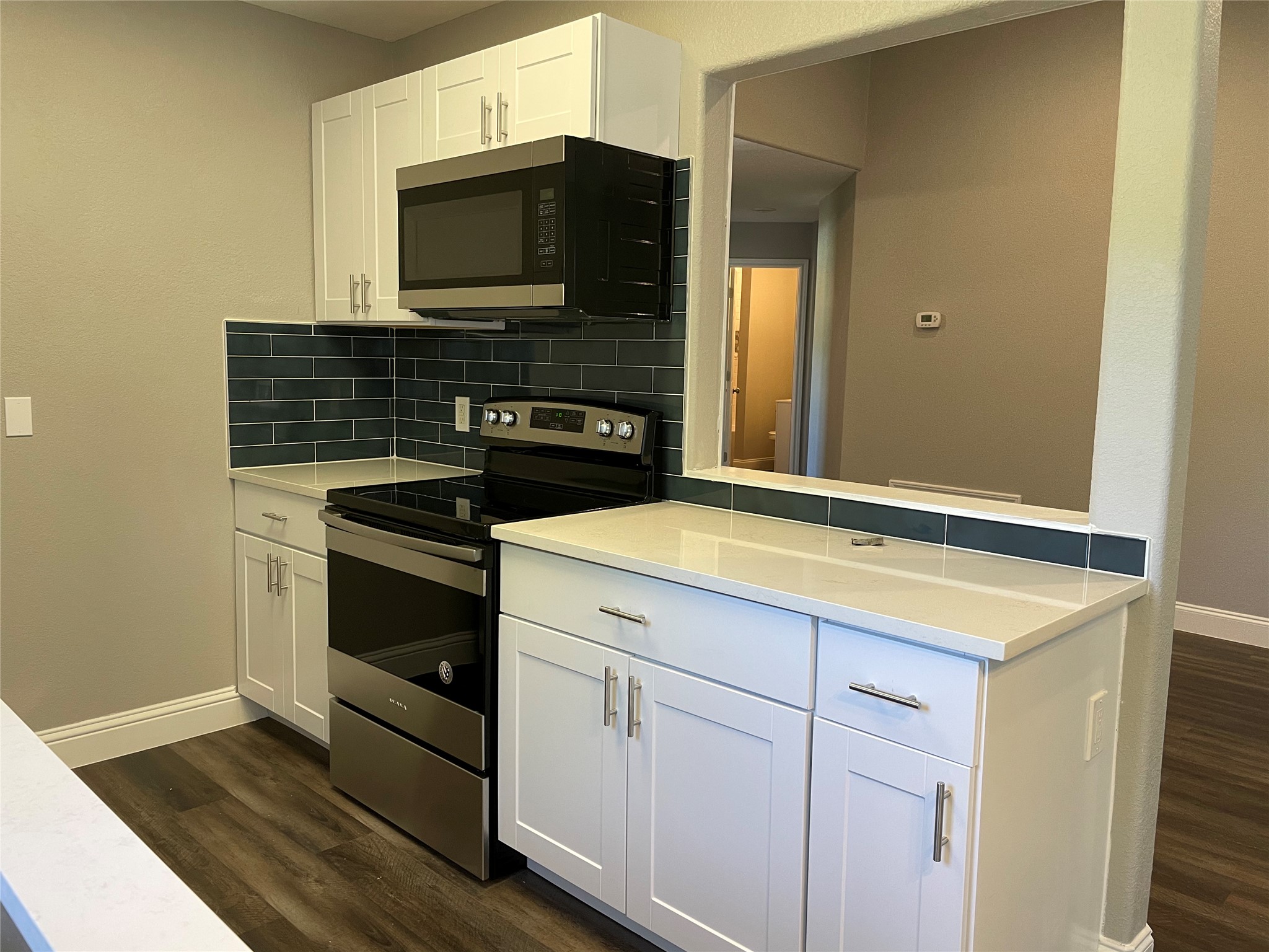 2004 Maple Street Georgetown, TX 78626 - Photo 10 of 31 Modern kitchen featuring white shaker cabinetry, stainless steel appliances, a dark subway tile backsplash, and light countertops