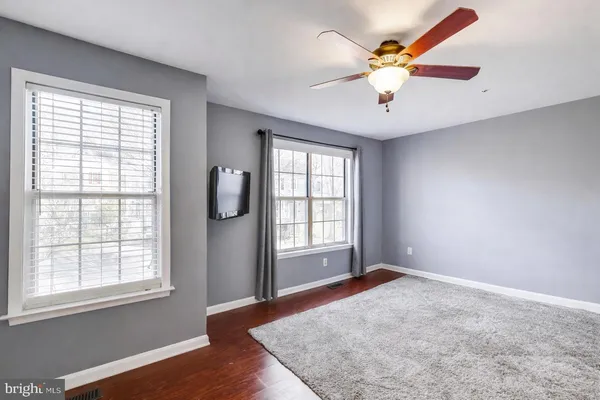 an empty room with windows and chandelier fan