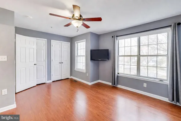 a view of empty room with wooden floor and fan