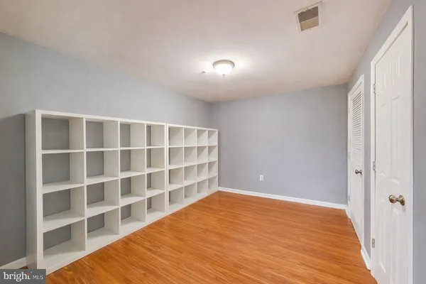 a view of an empty room with wooden floor and closet