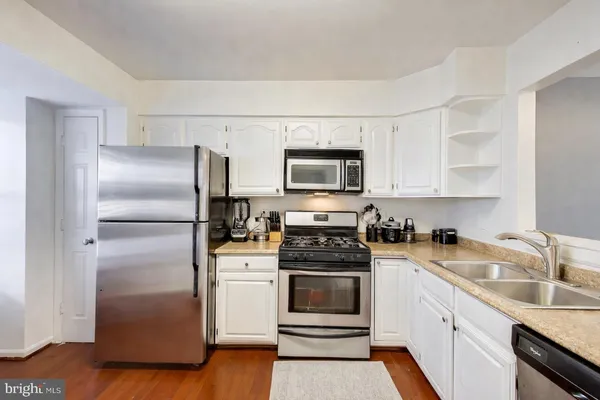a kitchen with cabinets stainless steel appliances and wooden floor