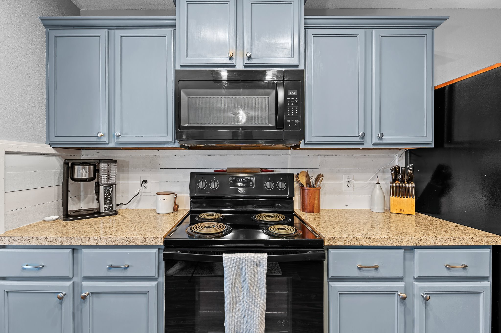 100 Wincliff Cove, Unit 13D Jarrell, TX 76537 - Photo 14 of 40 a kitchen with granite countertop a stove top oven microwave and cabinets
