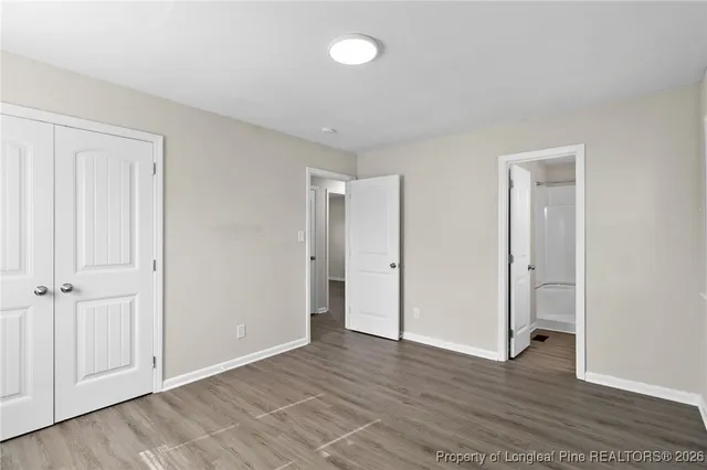 an empty room with wooden floor and closet area