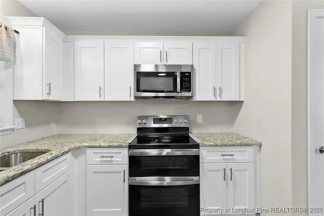 a kitchen with granite countertop white cabinets and black stainless steel appliances