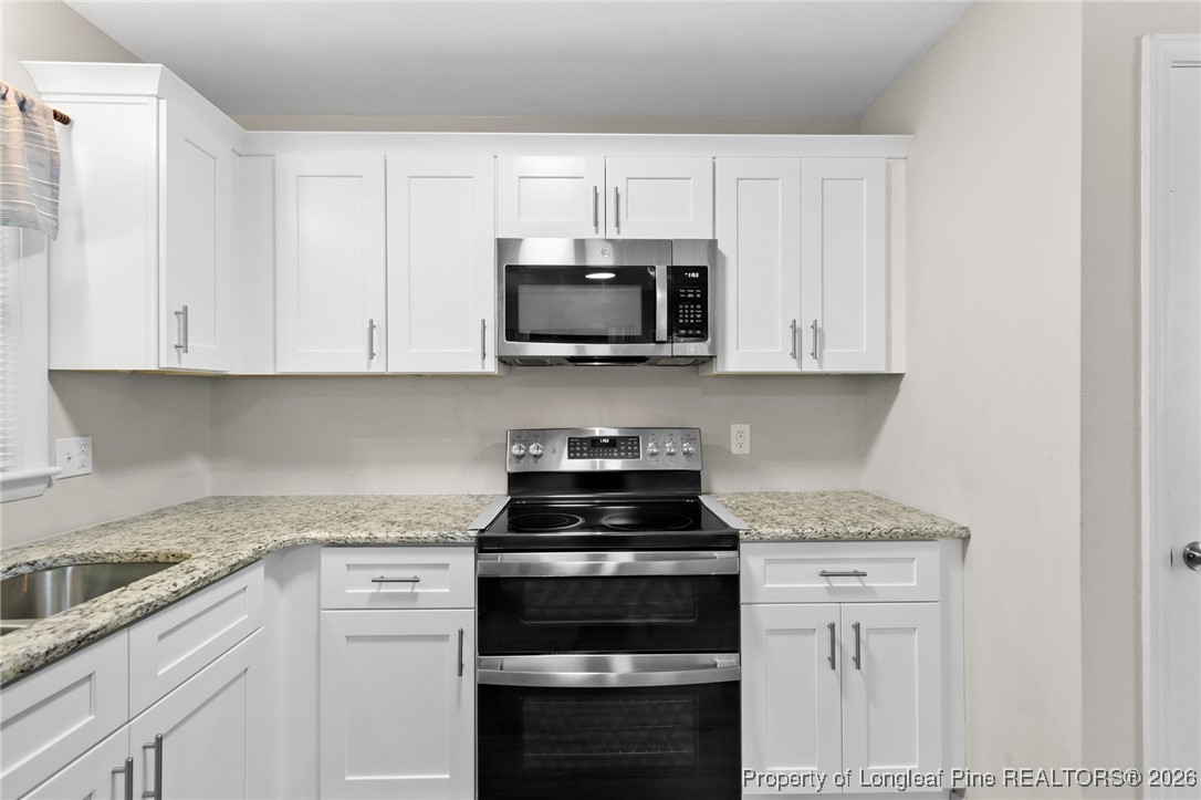 5414 Plateau Road Fayetteville, NC 28303 - Photo 10 of 27 a kitchen with granite countertop white cabinets and black stainless steel appliances