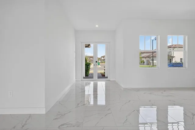 a kitchen with stainless steel appliances a stove a sink a refrigerator and white cabinets with wooden floor