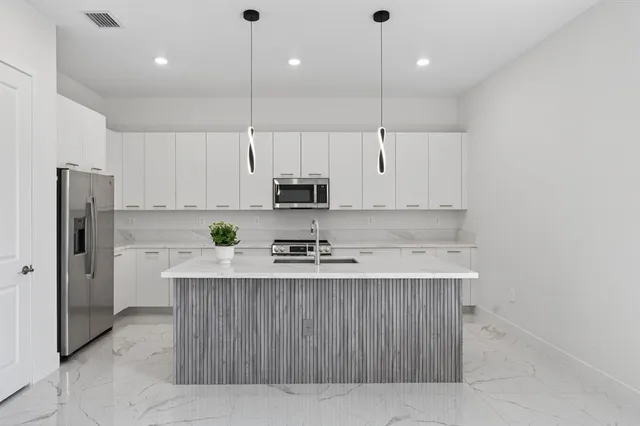 a kitchen with granite countertop a sink stainless steel appliances and living room view