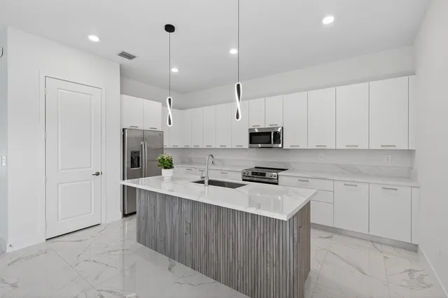 a kitchen with stainless steel appliances granite countertop a sink a refrigerator and a stove