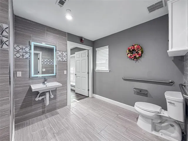 a bathroom with a sink a toilet and a large mirror