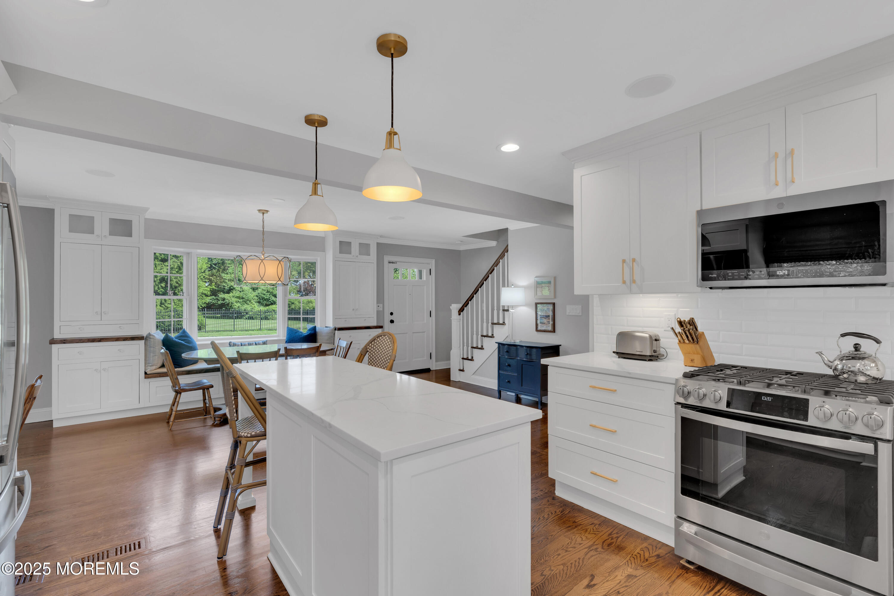 57 W River Road Rumson, NJ 07760 - Photo 5 of 44 a kitchen with a stove a sink a microwave a dining table and chairs with wooden floor