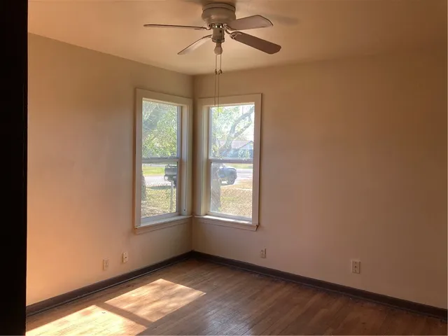 an empty room with chandelier fan and windows