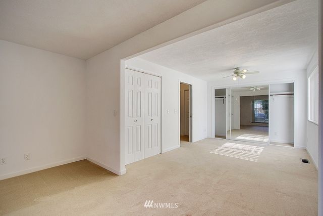 a view of an empty room with closet and a window