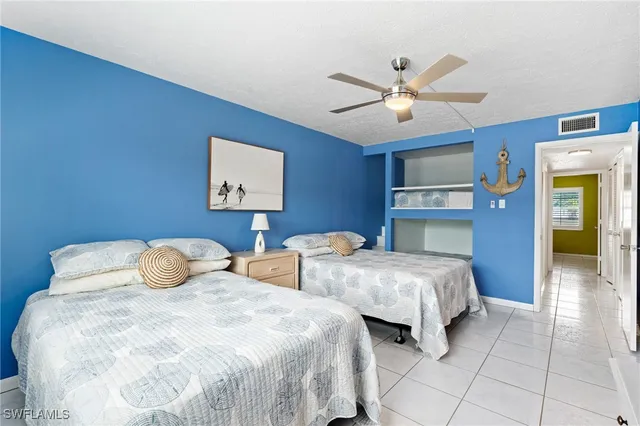 a bedroom with two beds and ceiling fan