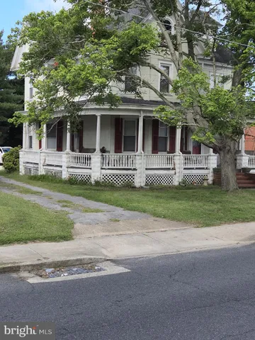 a front view of a house with a garden and trees