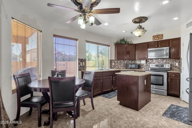 a kitchen with a dining table chairs stainless steel appliances and cabinets