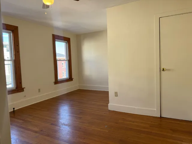 an empty room with wooden floor and windows