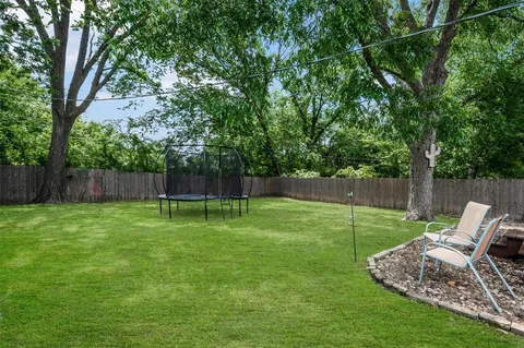 a view of a backyard with a slide trees and wooden fence