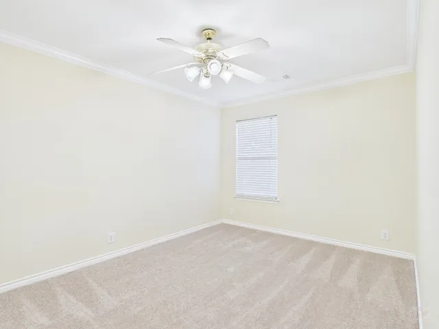 an empty room with chandelier fan and windows