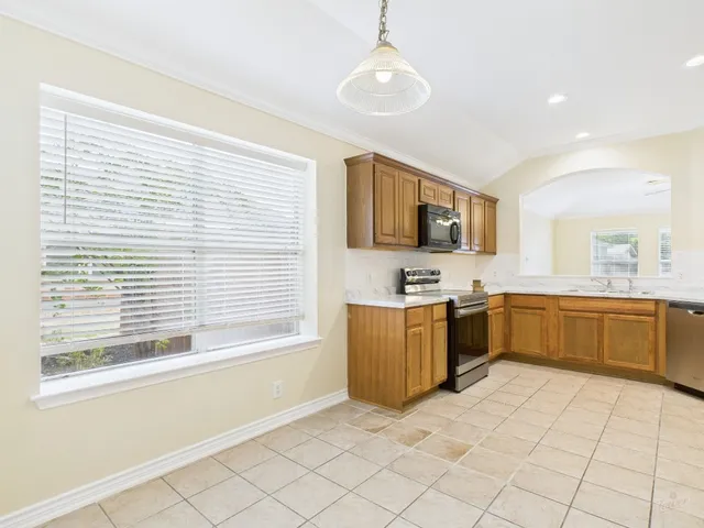 a large kitchen with stainless steel appliances granite countertop a stove a sink dishwasher a microwave oven with cabinets and wooden floor