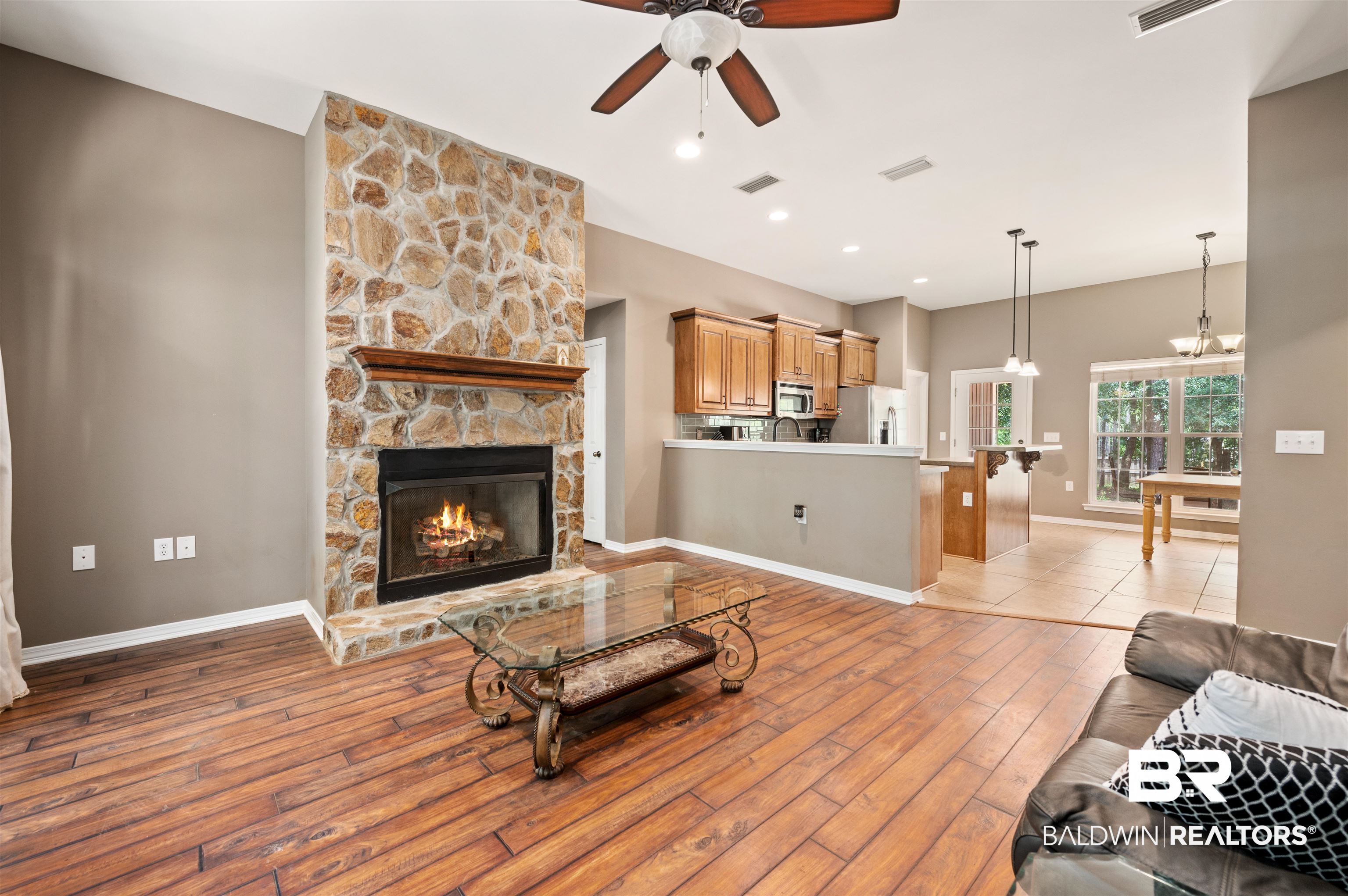 15240 Styx River Road Stapleton, AL 36578 - Photo 18 of 18 Living room with ceiling fan with notable chandelier, a stone fireplace, and light hardwood / wood-style floors