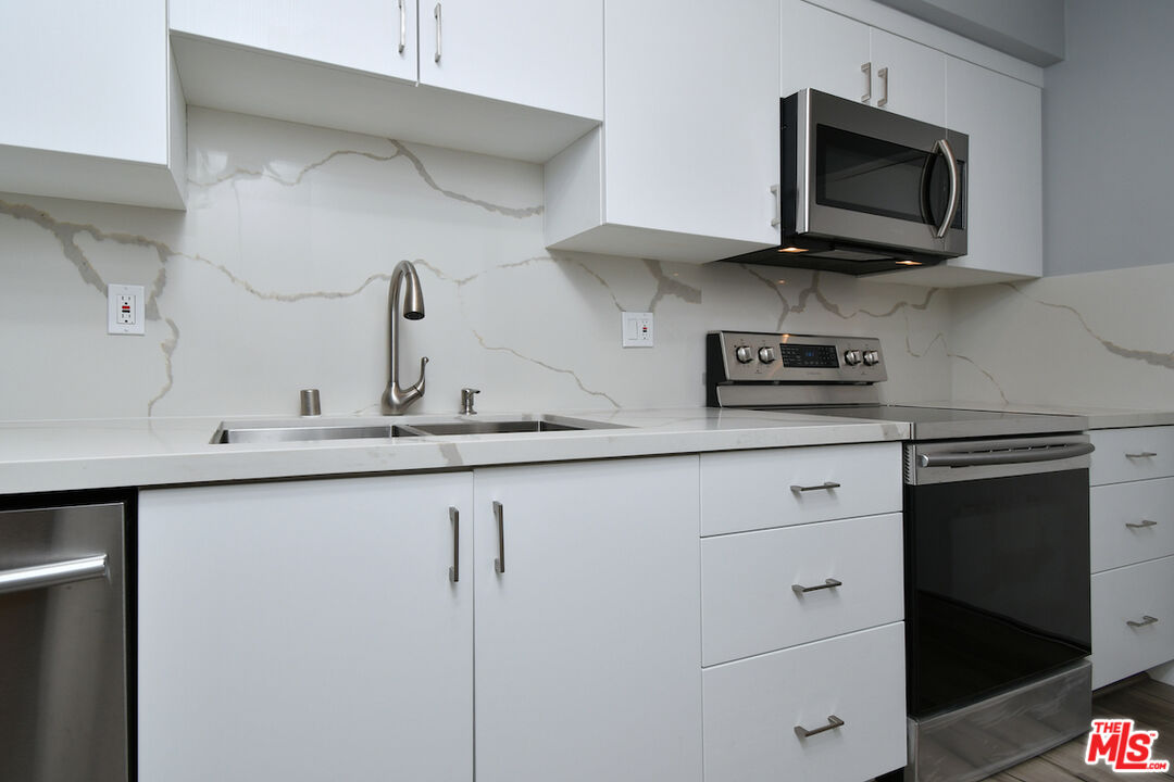 2345 Roscomare Road, Unit 205 Los Angeles, CA 90077 - Photo 18 of 50 a kitchen with stainless steel appliances granite countertop white cabinets and a stove top oven