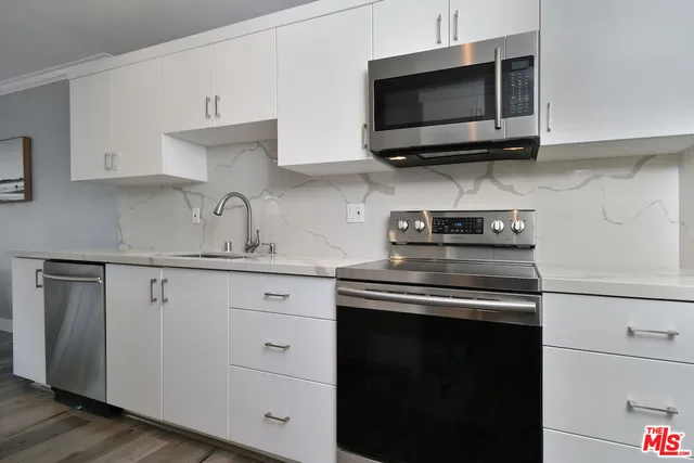a kitchen with stainless steel appliances a stove a microwave a sink and cabinets