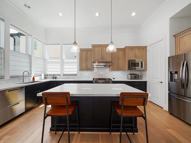 a kitchen with stainless steel appliances granite countertop a stove a sink refrigerator a dining table and chairs