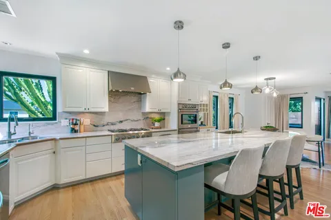 a kitchen with granite countertop a table chairs sink and refrigerator