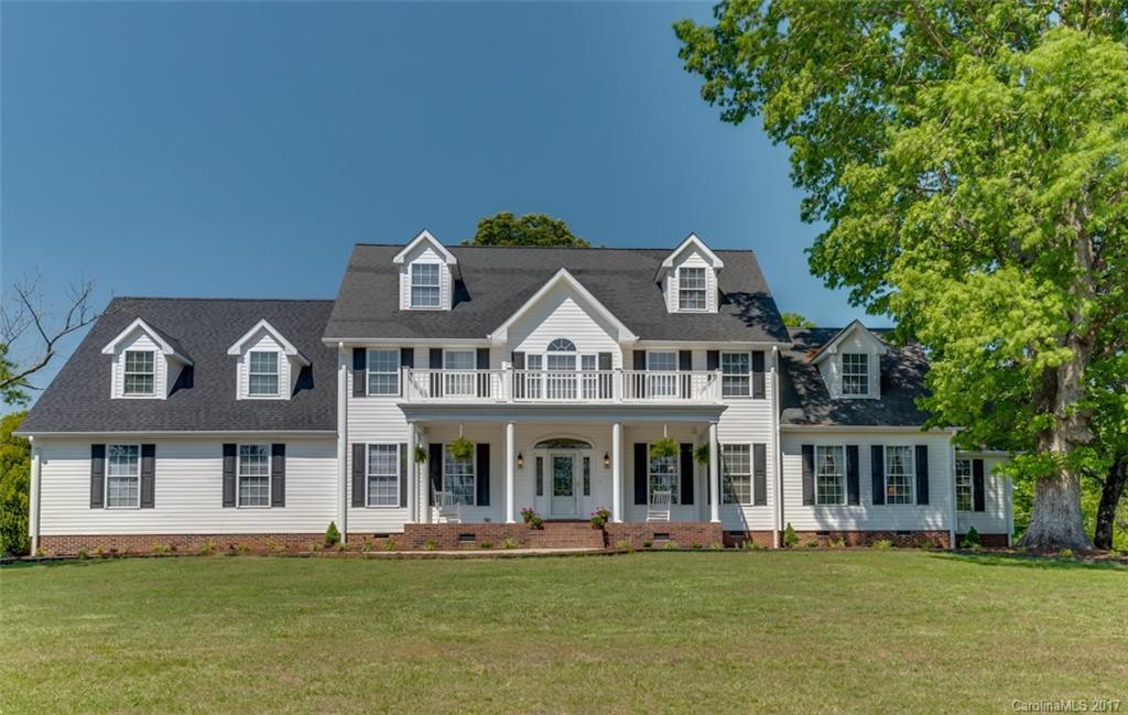 front view of a brick house with a big yard and large trees