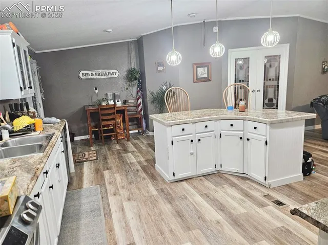 a large white kitchen with a stove a sink dishwasher and a fireplace with wooden floor