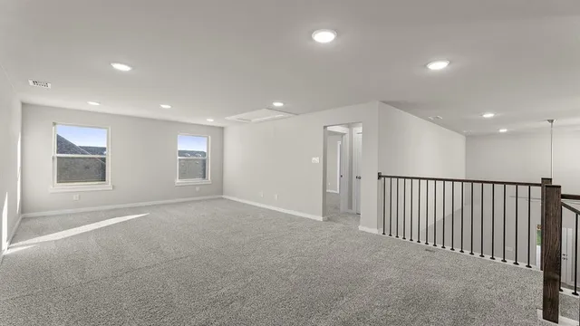 an empty room with wooden floor cabinet and windows