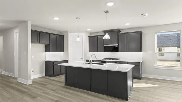 a large kitchen with a large counter top a sink stainless steel appliances and cabinets