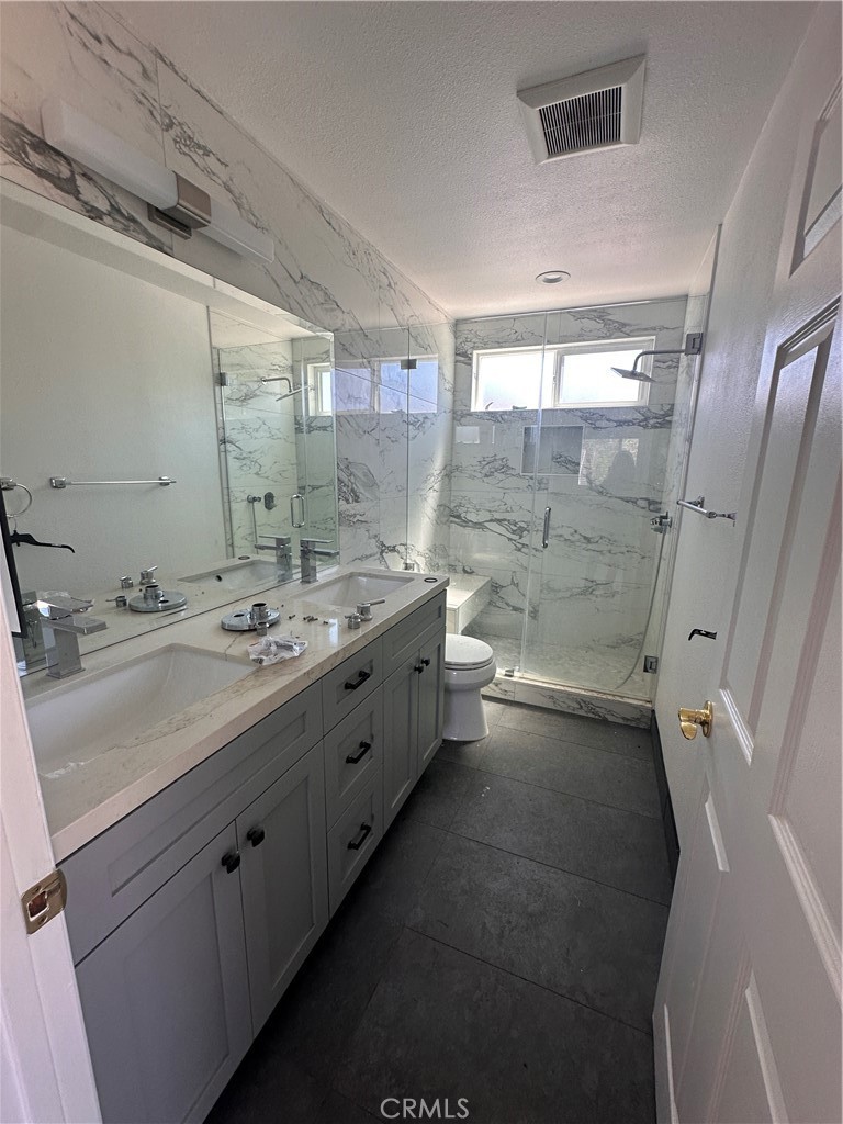 a bathroom with a double vanity sink toilet and shower
