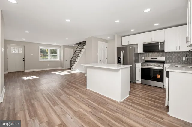 a view of kitchen with microwave a stove and wooden floor