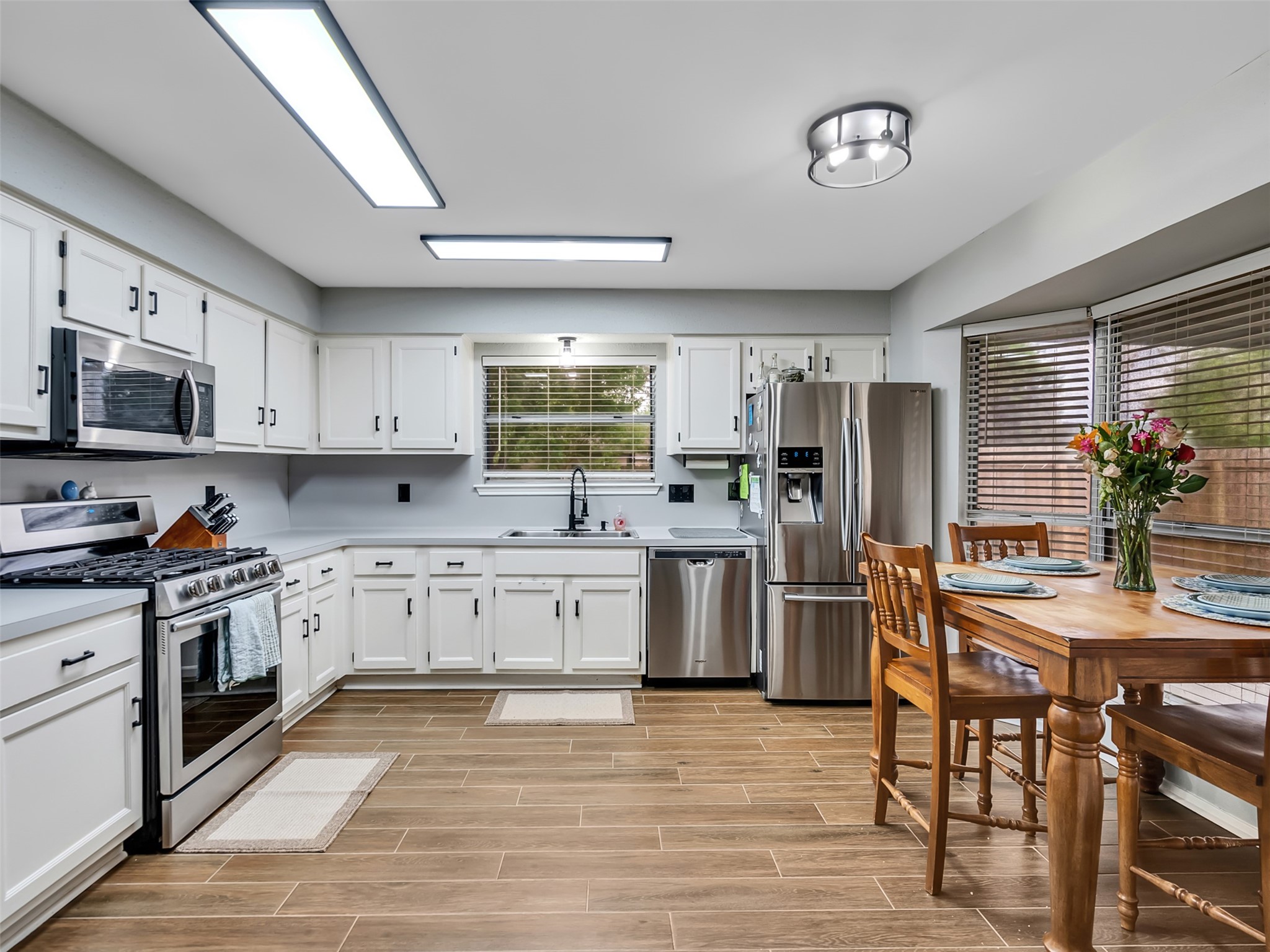 101 North Wagon Lane Angleton, TX 77515 - Photo 6 of 23 a kitchen with granite countertop a stove top oven a sink dishwasher a dining table and chairs with wooden floor