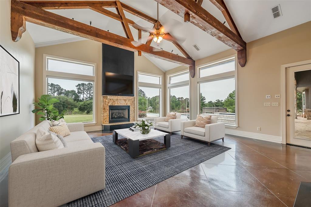 20389 County Road 178 Flint, TX 75762 - Photo 12 of 40 Vaulted ceiling with exposed wood beams, large picture windows, and a stone-clad fireplace with a dark hearth