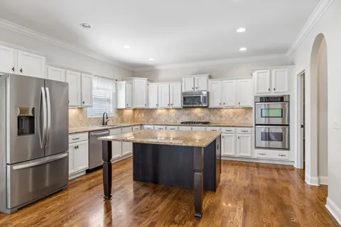 a kitchen with granite countertop white cabinets and stainless steel appliances