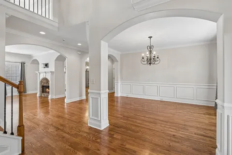 a view of a hallway with wooden floor windows and a chandelier