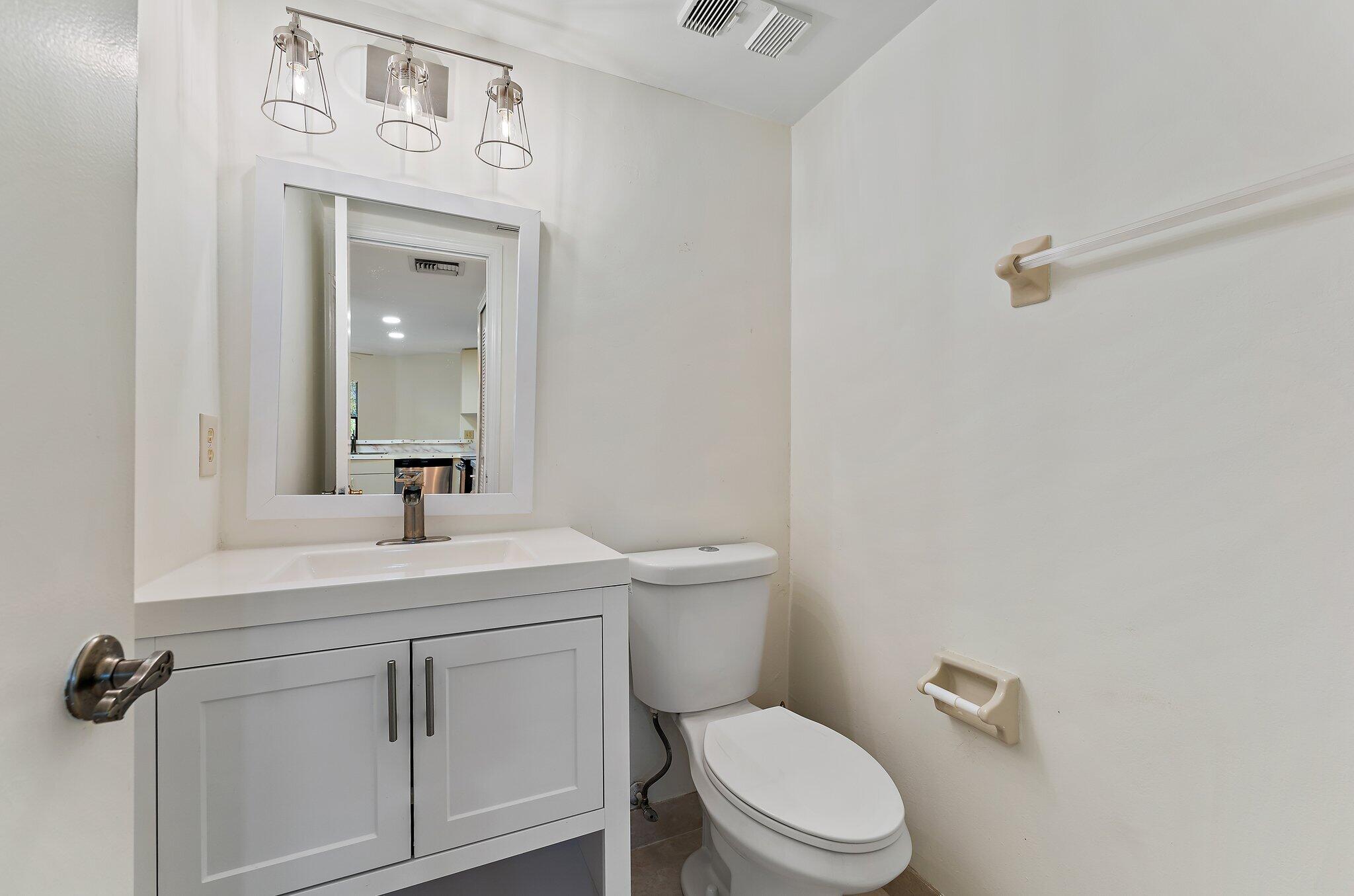3 Uno Lago Drive, Unit 3 Juno Beach, FL 33408 - Photo 12 of 31 a bathroom with a toilet sink vanity and mirror