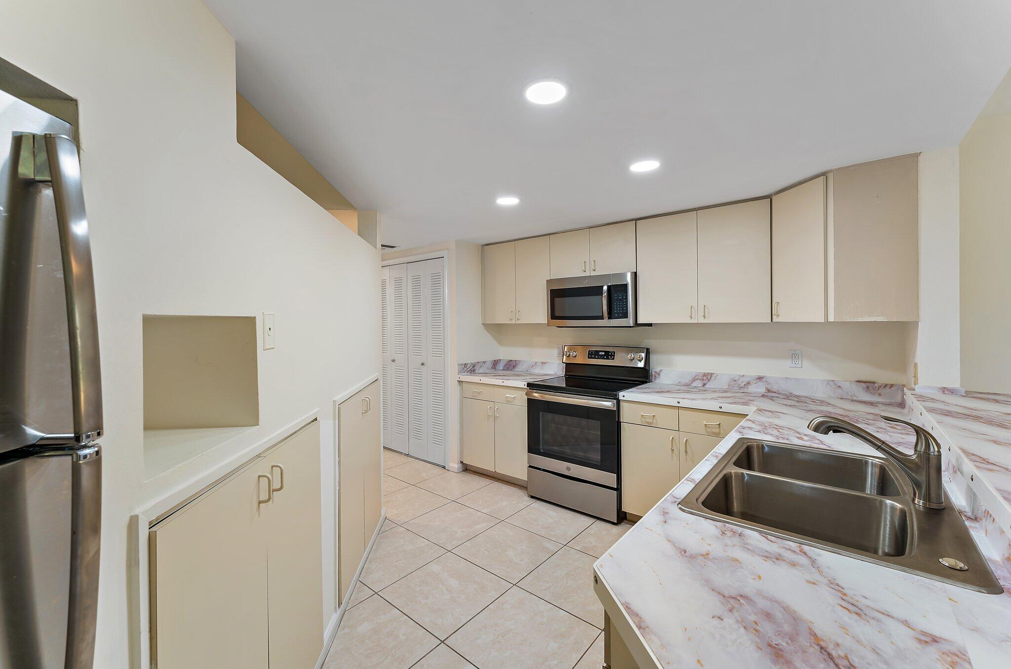 3 Uno Lago Drive, Unit 3 Juno Beach, FL 33408 - Photo 16 of 31 a kitchen with granite countertop white cabinets and stainless steel appliances