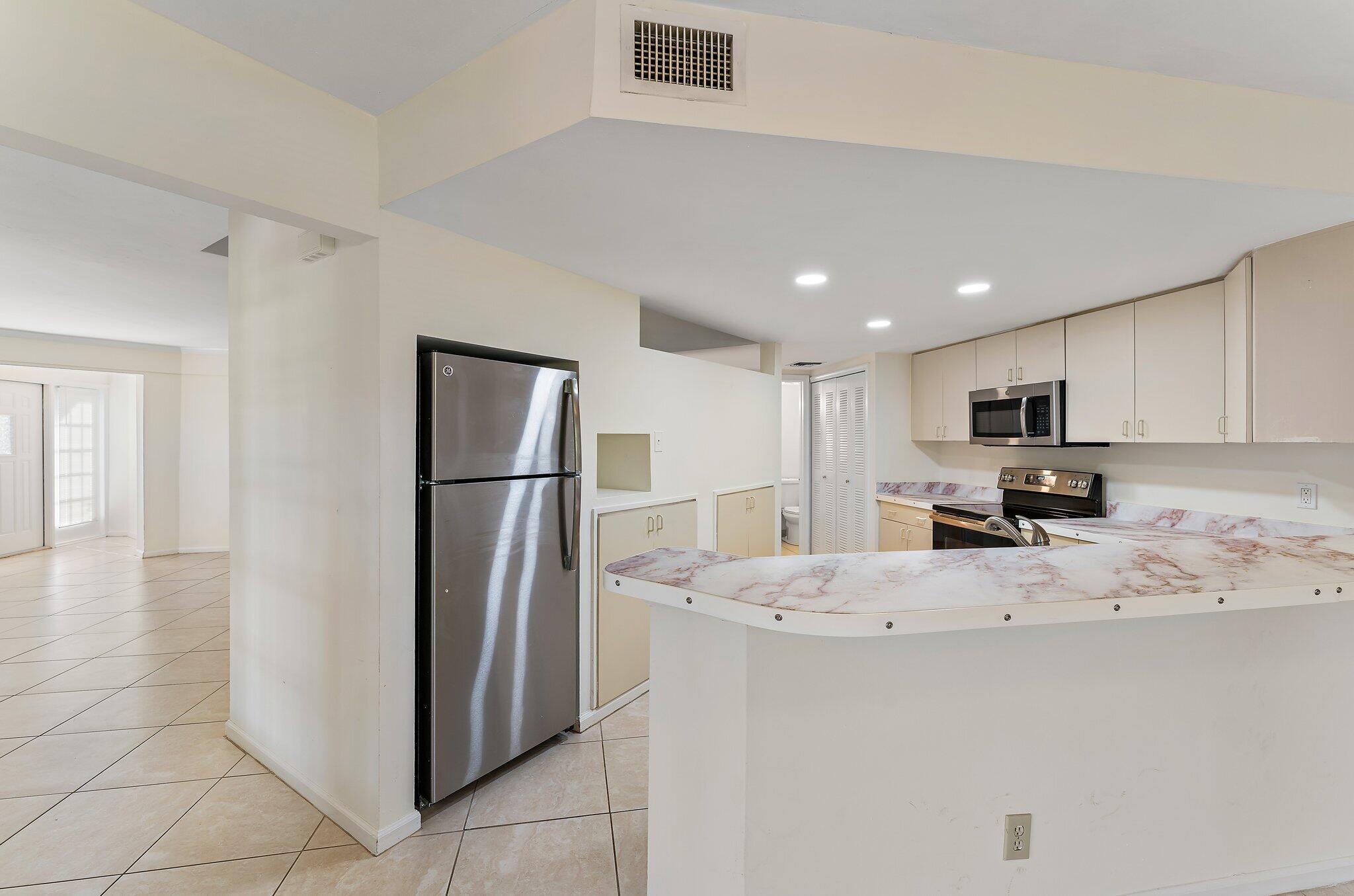3 Uno Lago Drive, Unit 3 Juno Beach, FL 33408 - Photo 17 of 31 a kitchen with stainless steel appliances granite countertop a refrigerator and a stove top oven