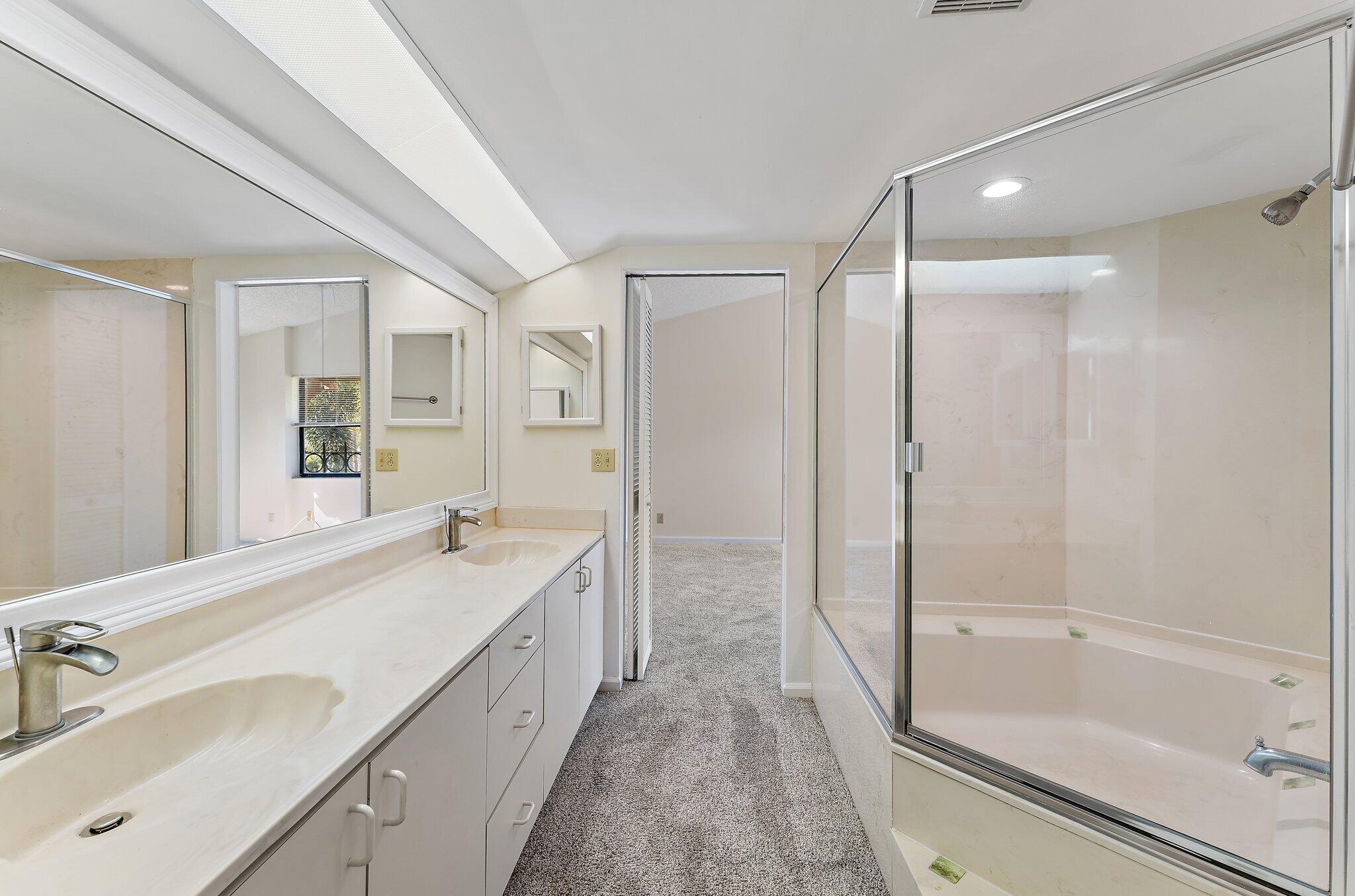 3 Uno Lago Drive, Unit 3 Juno Beach, FL 33408 - Photo 26 of 31 a spacious bathroom with a bathtub shower sink vanity and a mirror