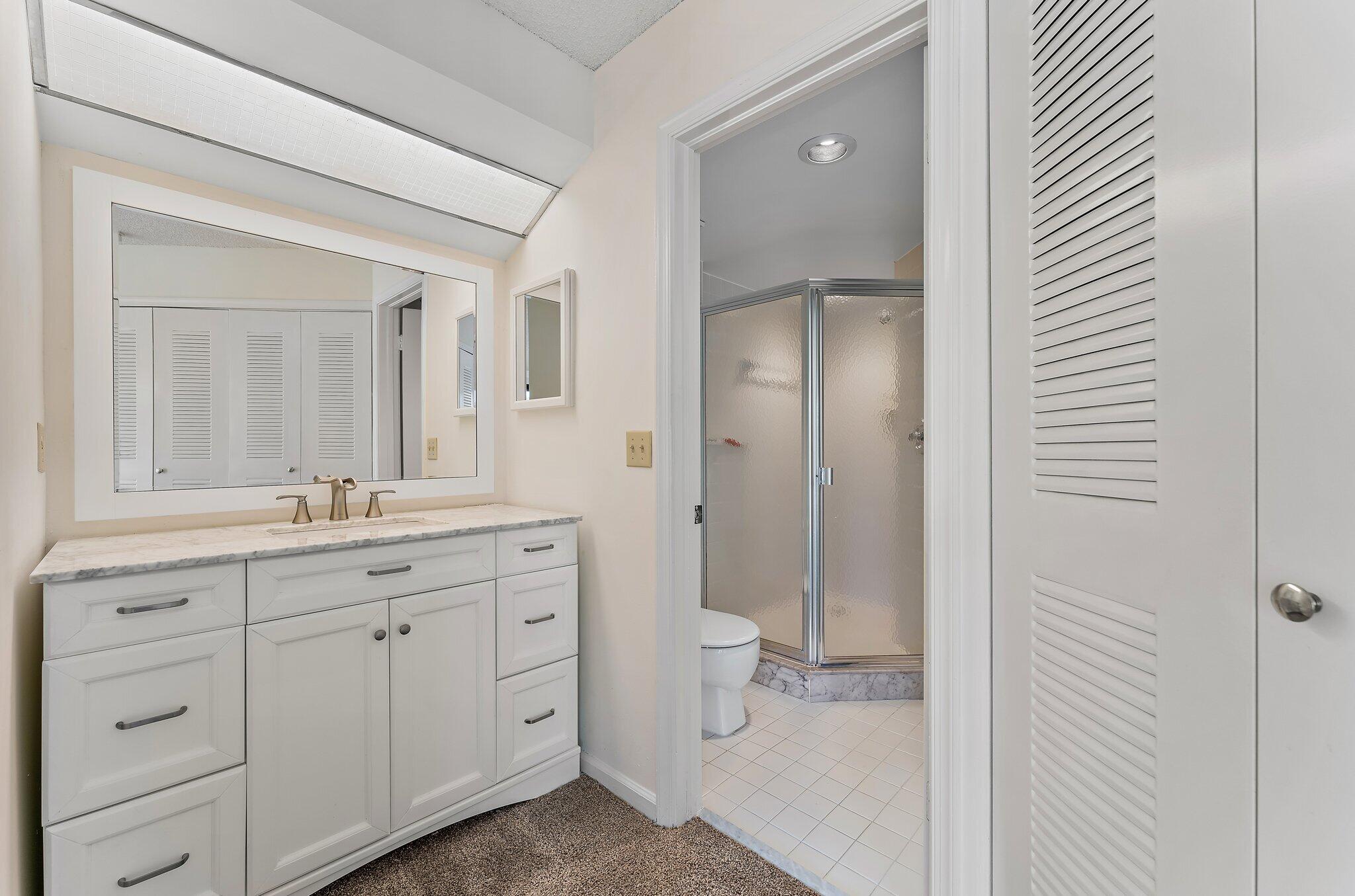 3 Uno Lago Drive, Unit 3 Juno Beach, FL 33408 - Photo 30 of 31 a bathroom with a granite countertop sink mirror and a toilet