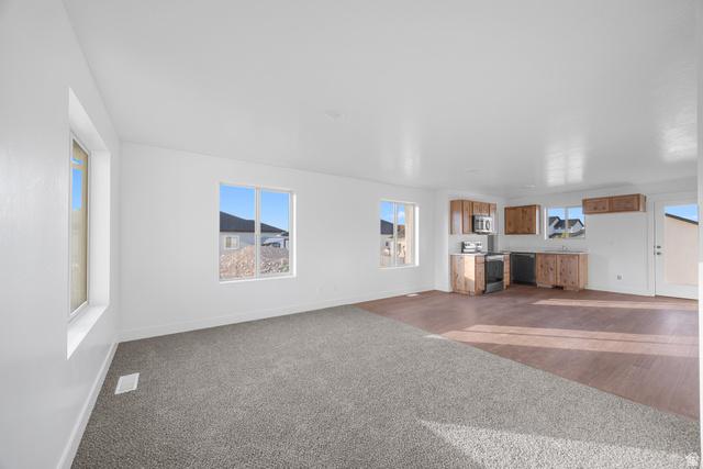 1563 South Deerbrook Road, Unit 267CHM Santaquin, UT 84655 - Photo 4 of 12 Open-concept living space featuring new carpet, wood-finish flooring, and white walls