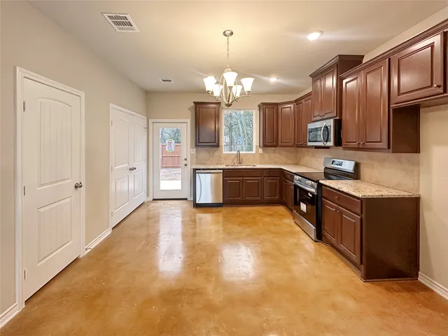 a large kitchen with granite countertop a large counter top and stainless steel appliances