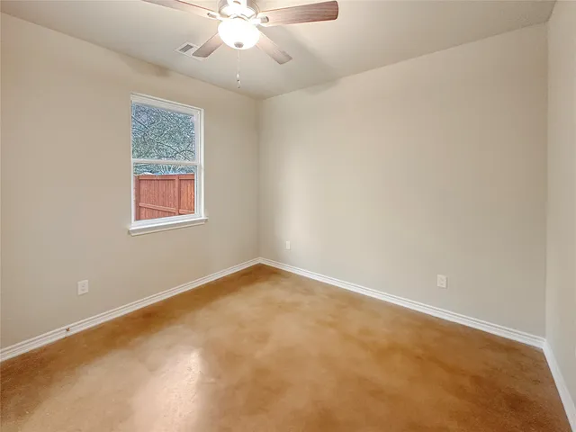 an empty room with a chandelier fan and windows
