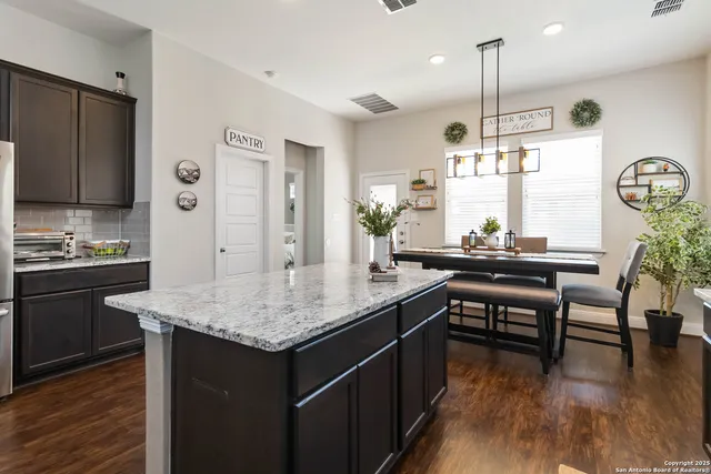 a kitchen with granite countertop a table chairs stove and wooden floor