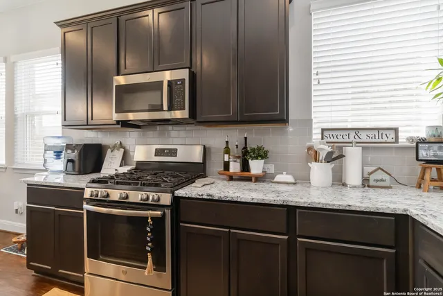a kitchen with granite countertop a sink a stove and microwave