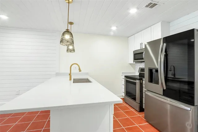 a kitchen with stainless steel appliances granite countertop a sink and a refrigerator