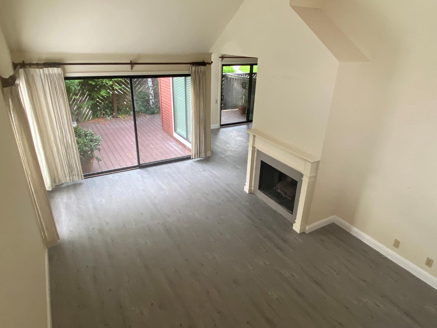 910 Wharfside Road San Mateo, CA 94404 - Photo 6 of 14 an empty room with wooden floor fireplace and windows